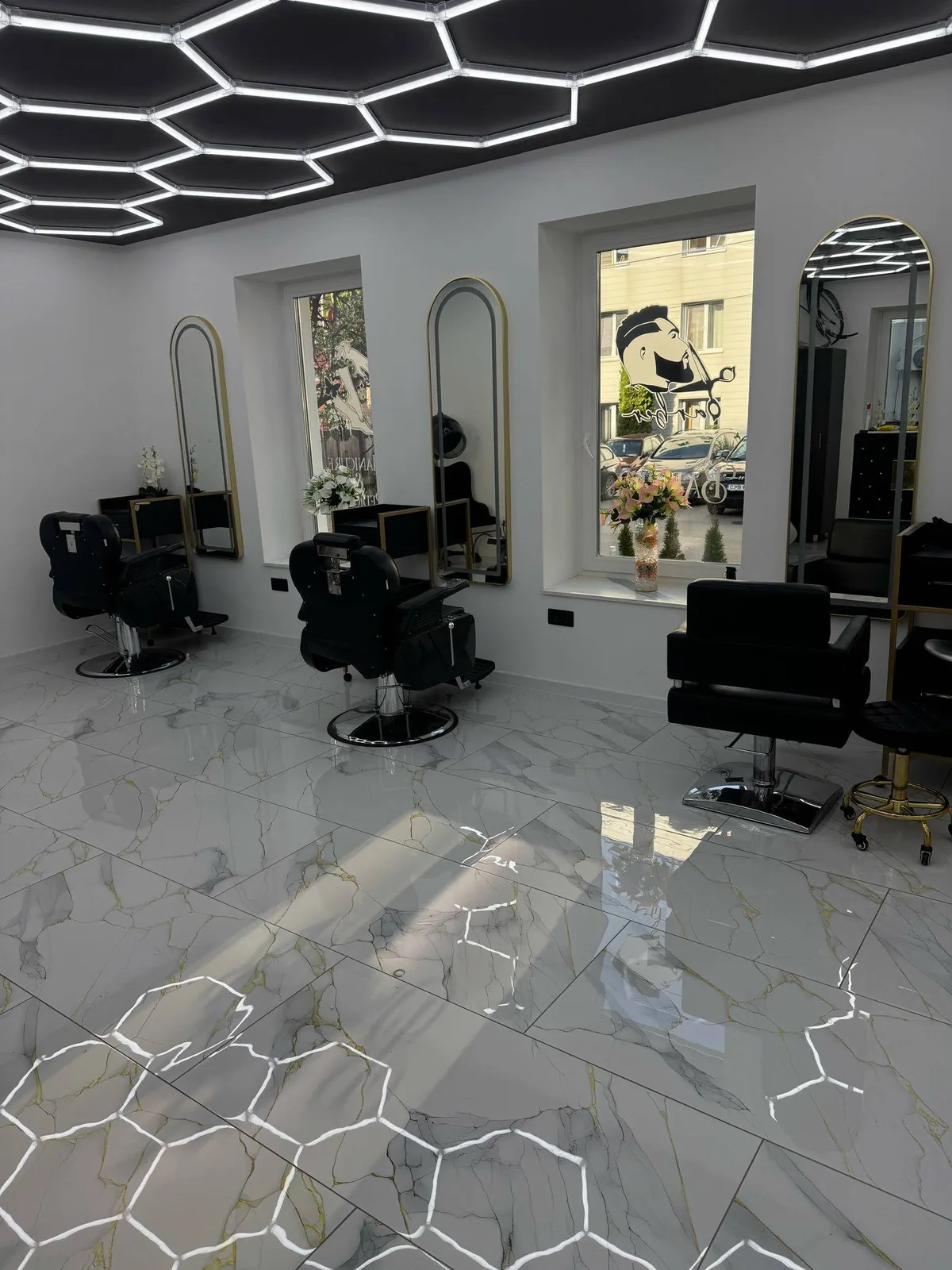 Interiorul Royal Vibe Salon, cu oglinzi aurii, fotolii negre și iluminare geometrică